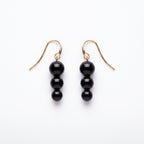 Noir Cascade black bead drop earrings on a white background