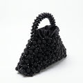 Angled view of the Velvet Caviar black crystal bag, handle and satin lining