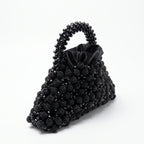 Angled view of the Velvet Caviar black crystal bag, handle and satin lining