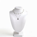 Layered pearl necklace with silver heart pendant on a white jewelry bust