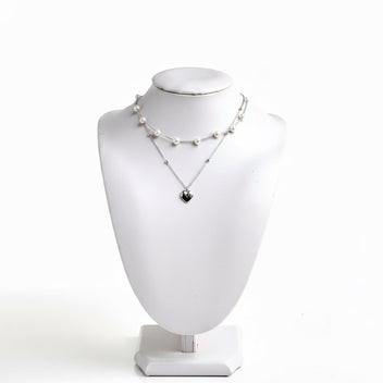 Layered pearl necklace with silver heart pendant on a white jewelry bust