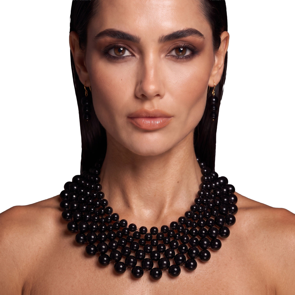 Model wearing the LUMI The Noir Cascade Jewelry Set featuring a black statement necklace and matching earrings