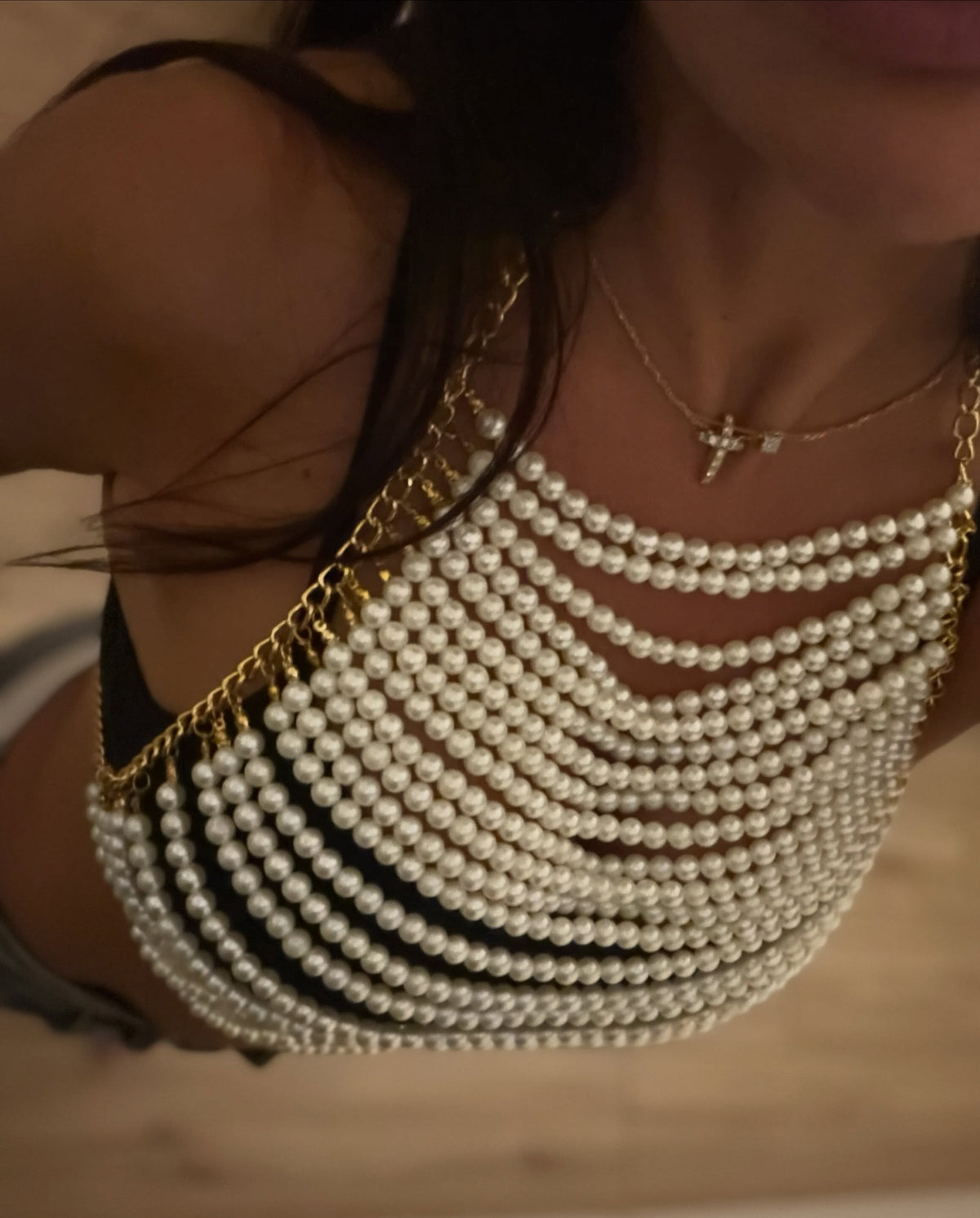 Close-up of Catherine Chidiac wearing layered white pearl LUMI body jewelry with gold chain details.