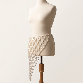 Angled view of the handmade Celeste white pearl waist belt showing its asymmetric cascading lattice design.