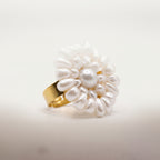 Angled studio view of the handmade Alba Pearl Bloom Ring by LUMI, featuring a sculptural white pearl flower with layered pearl accents and a gold-tone adjustable band.