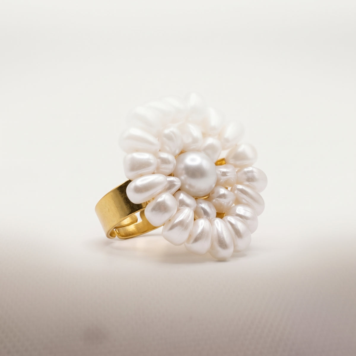 Angled studio view of the handmade Alba Pearl Bloom Ring by LUMI, featuring a sculptural white pearl flower with layered pearl accents and a gold-tone adjustable band.