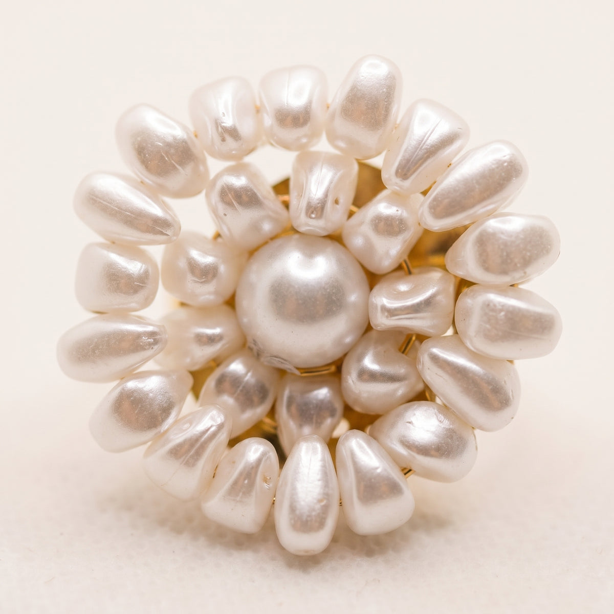 Macro photograph of the handmade Alba Pearl Bloom Ring by LUMI, highlighting its central white pearl surrounded by layered teardrop-shaped pearl beads arranged in a floral design.