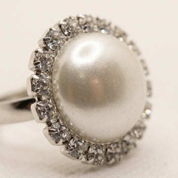 Detailed close-up of LUMI's Celestia Pearl Halo Ring – White, featuring a smooth white pearl encircled by faceted clear glass crystals in a silver-tone setting.