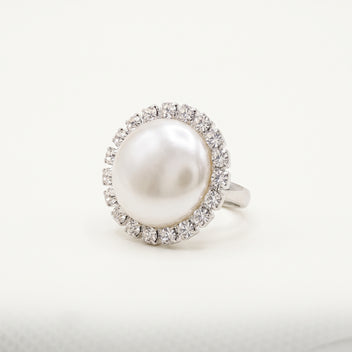 Handmade Celestia Pearl Halo Ring – White by LUMI, featuring a large white pearl surrounded by clear glass crystals in a polished silver-tone metal setting against a white background.