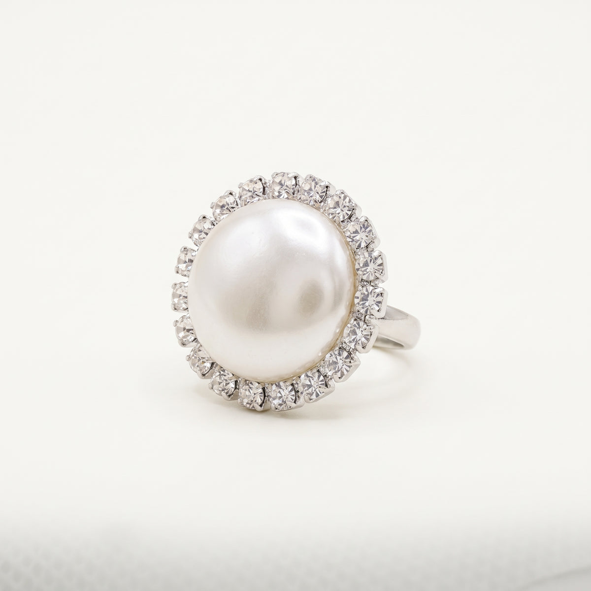 Handmade Celestia Pearl Halo Ring – White by LUMI, featuring a large white pearl surrounded by clear glass crystals in a polished silver-tone metal setting against a white background.
