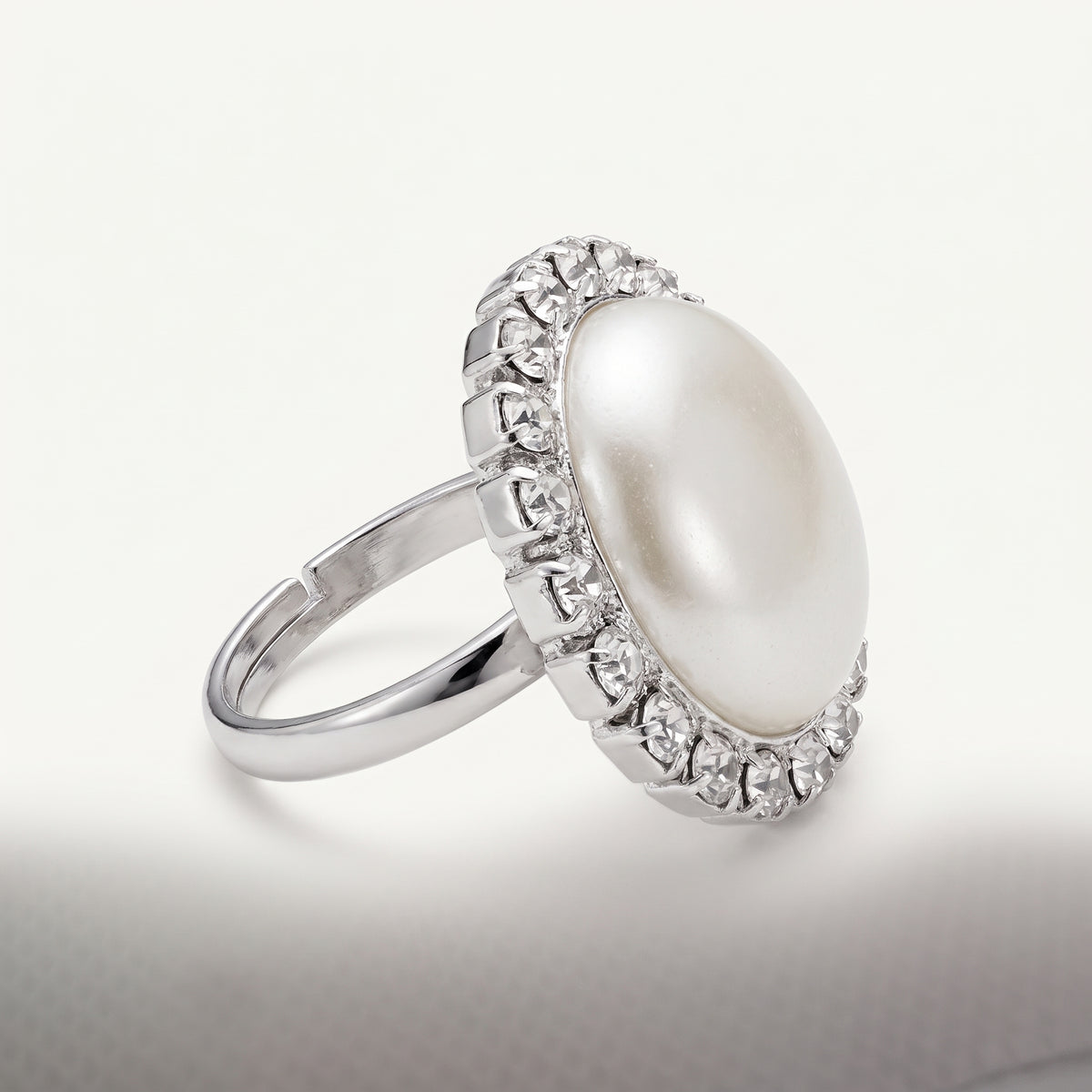 Side view of the Celestia Pearl Halo Ring – White by LUMI, highlighting its raised white pearl centerpiece, surrounding clear glass crystals and adjustable silver-tone metal band.