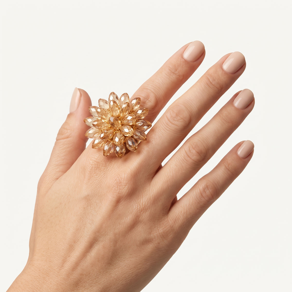 Close-up of a hand wearing the handmade Champagne Crystal Bloom Ring by LUMI, showcasing its statement floral silhouette and warm champagne crystal details.