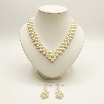 The Elara Pearl Jewelry Set by LUMI featuring a handmade ivory pearlescent necklace displayed on a cream jewelry bust with matching pearl drop earrings.