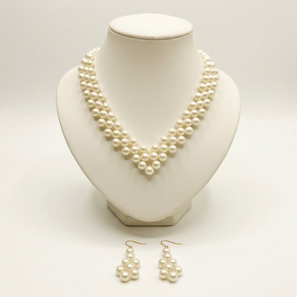 The Elara Pearl Jewelry Set by LUMI featuring a handmade ivory pearlescent necklace displayed on a cream jewelry bust with matching pearl drop earrings.