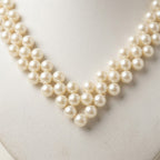 Detailed close-up of the Elara handmade ivory pearl necklace by LUMI, highlighting layered pearlescent beadwork arranged in an elegant V-shaped design.