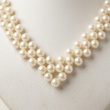 Detailed close-up of the Elara handmade ivory pearl necklace by LUMI, highlighting layered pearlescent beadwork arranged in an elegant V-shaped design.