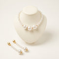 Handmade Éloise Pearl Trio Jewelry Set – White by LUMI, featuring a white pearl necklace with three large central pearls and matching long pearl drop earrings with gold-tone details on an ivory display.