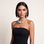 Fashion model wearing LUMI's Éloise Pearl Trio Jewelry Set – White, featuring a white pearl necklace with three prominent central pearls and matching long pearl drop earrings, styled with a black strapless dress.