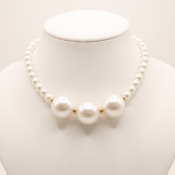 Close-up of LUMI's handmade Éloise Pearl Trio Necklace, highlighting three large luminous white pearls surrounded by smaller round pearl beads and polished gold-tone spacer accents.