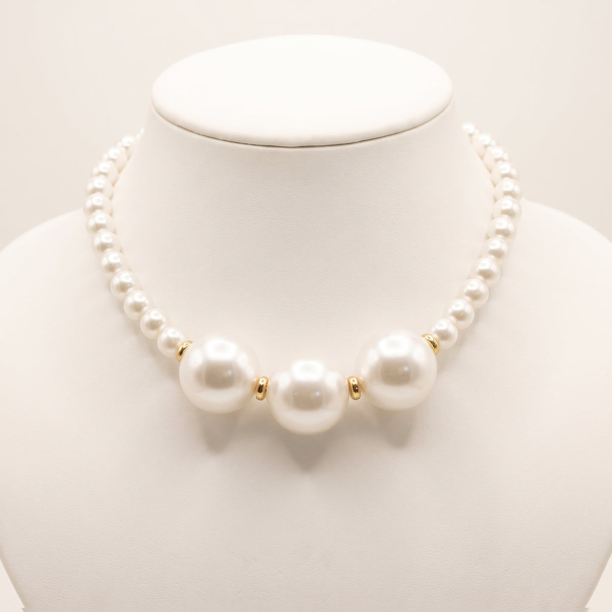 Close-up of LUMI's handmade Éloise Pearl Trio Necklace, highlighting three large luminous white pearls surrounded by smaller round pearl beads and polished gold-tone spacer accents.