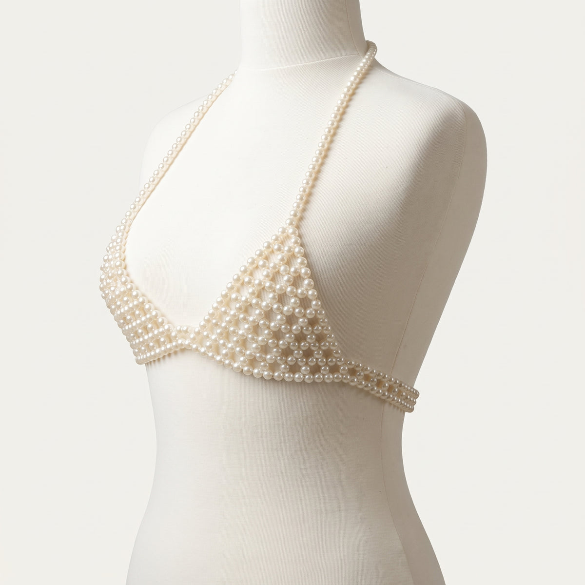 Handmade ivory pearl bra top by LUMI, shown on a white mannequin in a three-quarter studio view, highlighting the beaded cups and pearl straps.