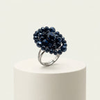 Angled studio view of LUMI's handmade Vesper Crystal Cluster Ring – Navy, highlighting its clustered faceted navy glass crystals and adjustable silver-tone metal band against a white background.