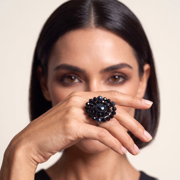 Fashion model wearing the handmade Vesper Crystal Cluster Ring – Navy by LUMI, holding her hand near her face to showcase the oversized navy glass crystal cluster design and silver-tone band.