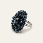 Handmade Vesper Crystal Cluster Ring – Navy by LUMI, featuring a dimensional arrangement of faceted navy glass crystal beads and an adjustable silver-tone metal band on a white studio pedestal.