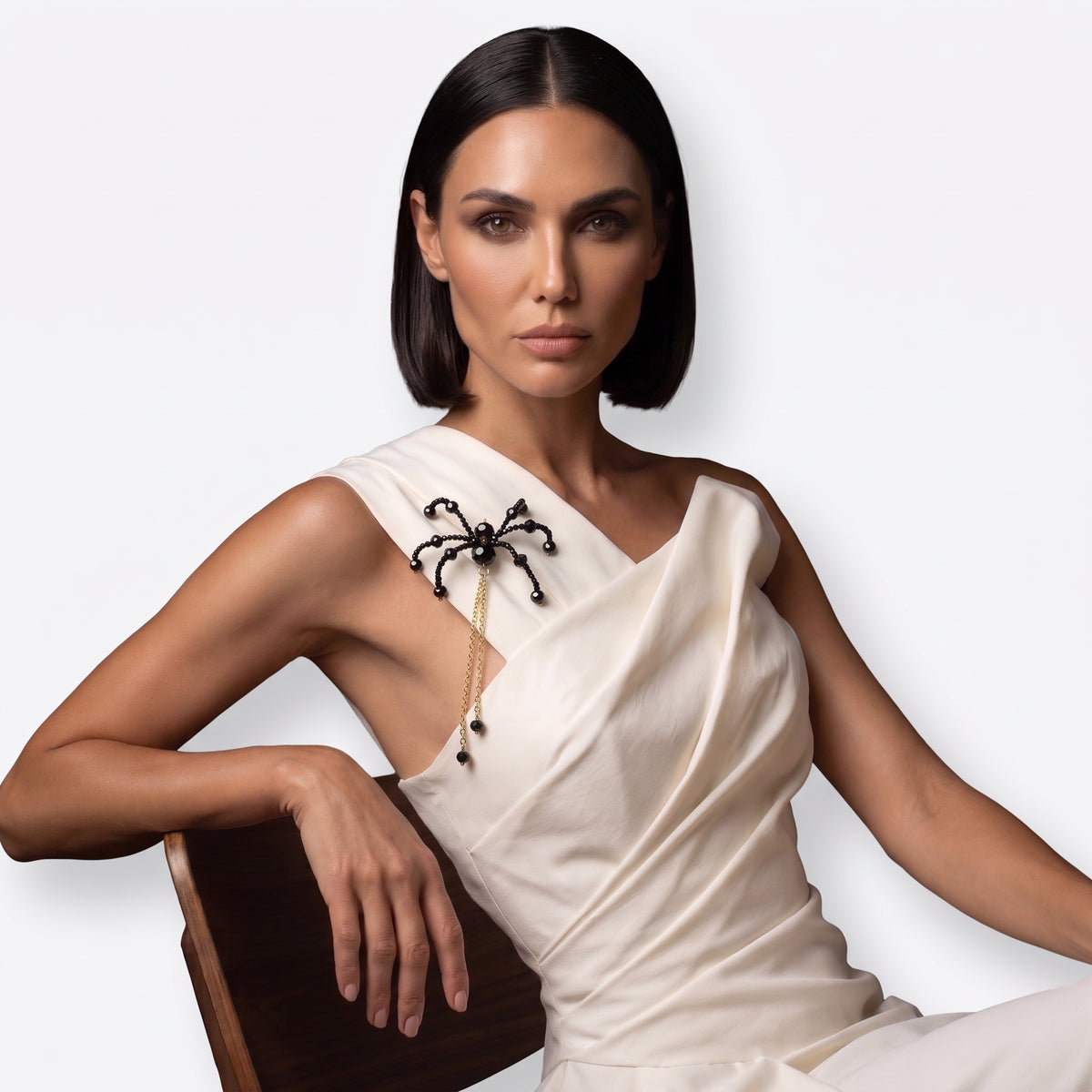 Woman wearing the Noir Crystal Spider Brooch on an ivory dress as a statement shoulder accessory.