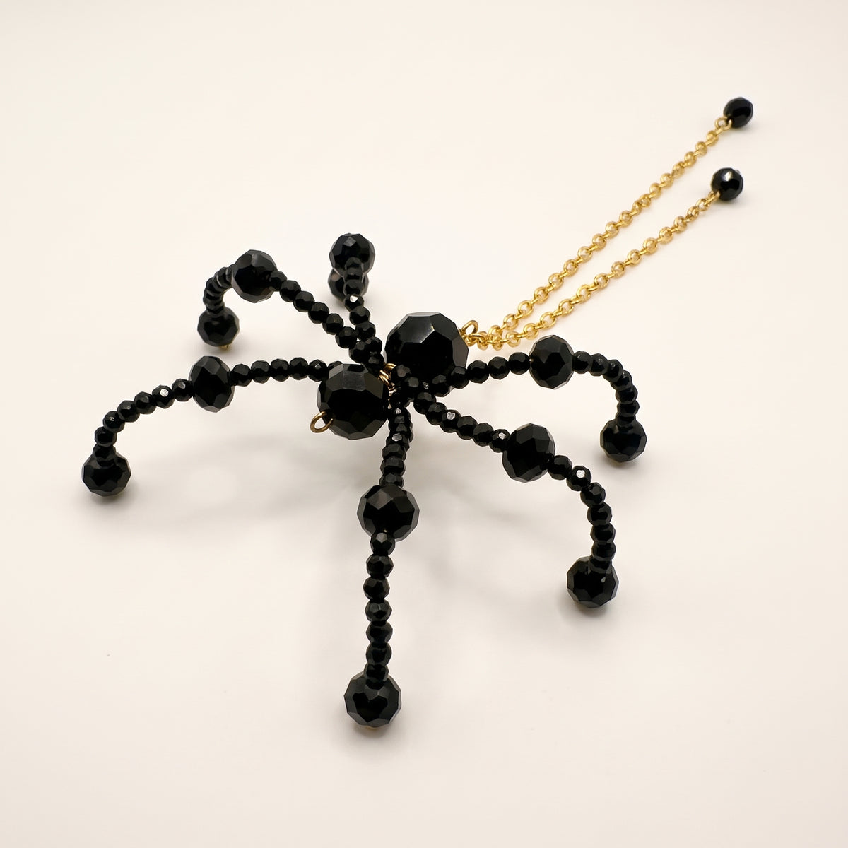 Handmade Noir Crystal Spider Brooch with faceted black crystal beads and gold-tone chain drops by LUMI.