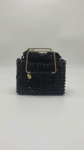 Video of the LUMI Noir Étoile Crystal Handbag, featuring black crystal beading, a polished gold-tone handle, and black satin lining.