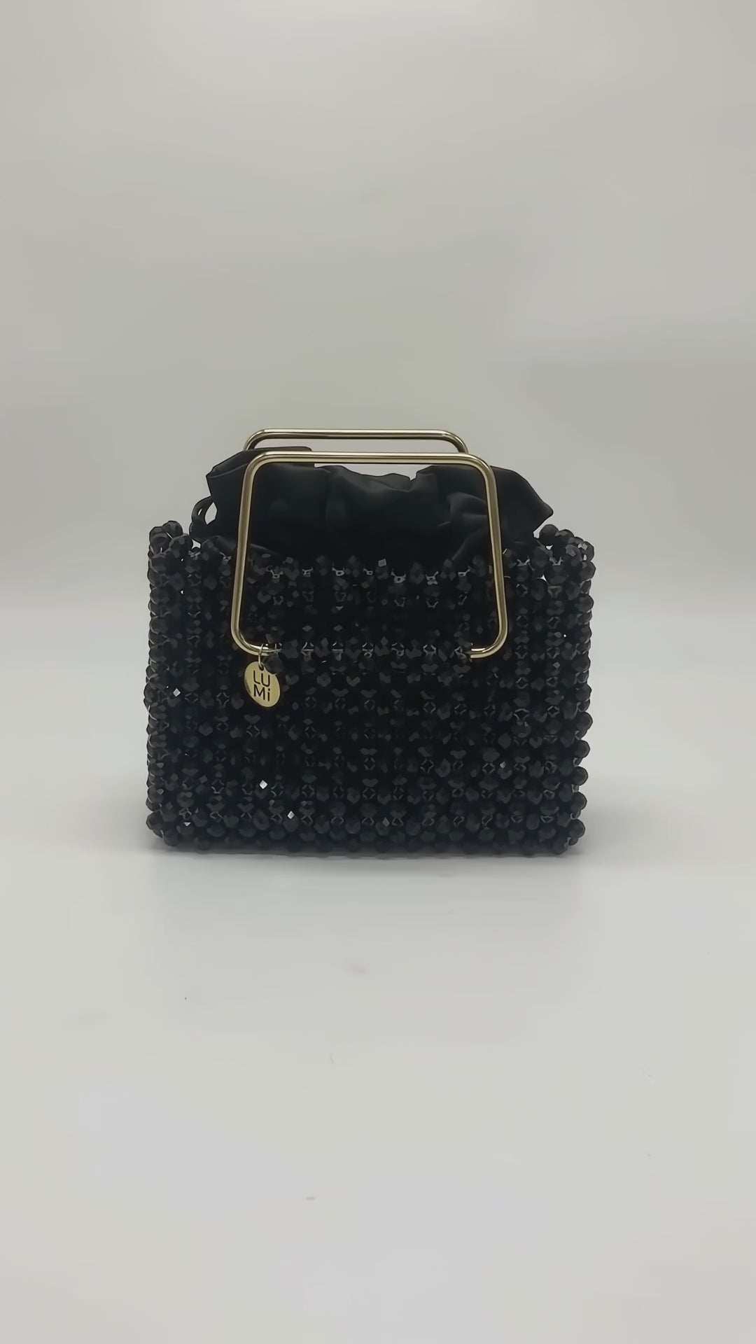 Video of the LUMI Noir Étoile Crystal Handbag, featuring black crystal beading, a polished gold-tone handle, and black satin lining.