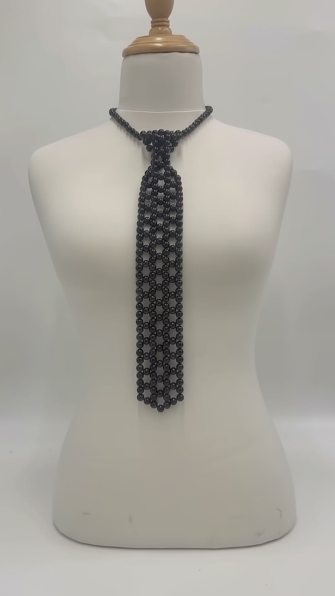 The Onyx Pearl Necktie in black pearls with an adjustable chain, shown in a studio product video.