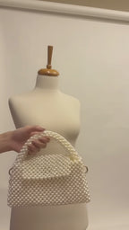 Video of The Nacre Bag by LUMI showing the pearl exterior, structured handle, gold-tone chain strap and satin-lined interior.
