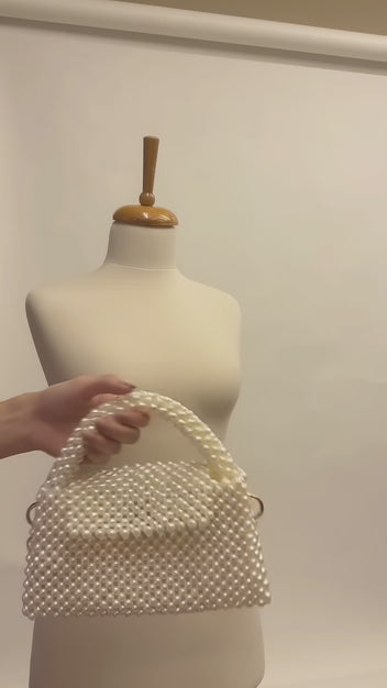 Video of The Nacre Bag by LUMI showing the pearl exterior, structured handle, gold-tone chain strap and satin-lined interior.