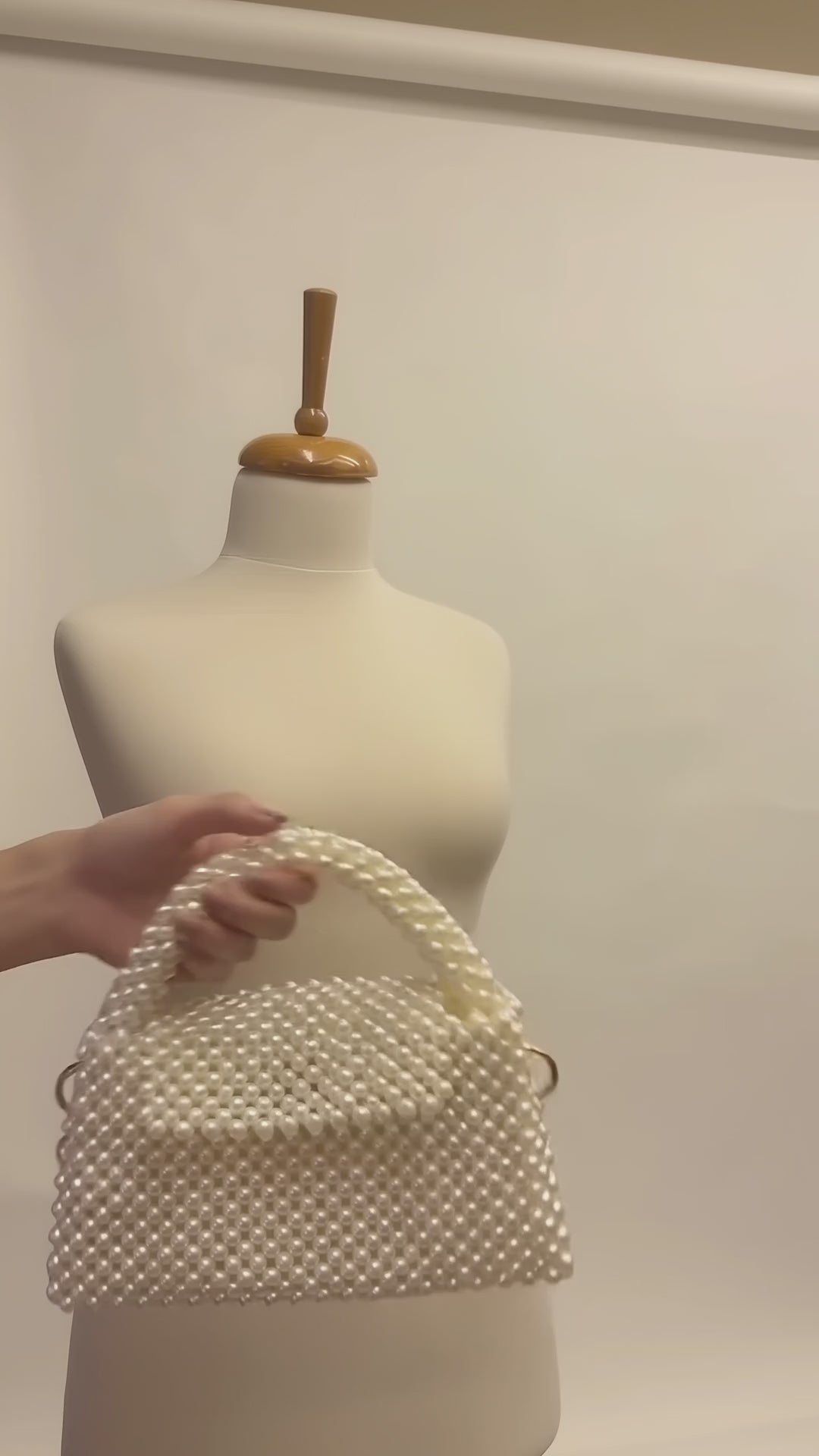 Video of The Nacre Bag by LUMI showing the pearl exterior, structured handle, gold-tone chain strap and satin-lined interior.