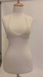 Studio video showcasing LUMI's handmade ivory pearl bra top on a white mannequin, highlighting the pearl beadwork, halter straps and structured design.