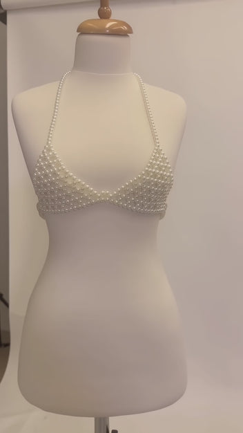 Studio video showcasing LUMI's handmade ivory pearl bra top on a white mannequin, highlighting the pearl beadwork, halter straps and structured design.