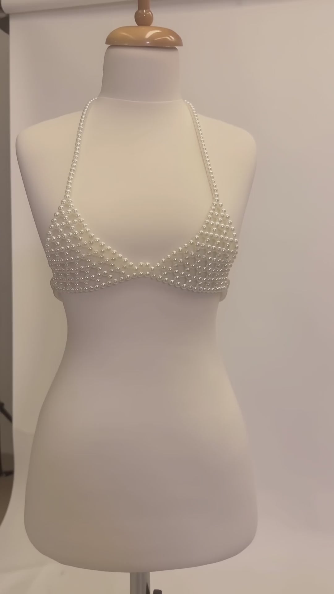 Studio video showcasing LUMI's handmade ivory pearl bra top on a white mannequin, highlighting the pearl beadwork, halter straps and structured design.