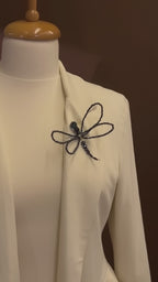 Luxury editorial video featuring LUMI's handmade black crystal dragonfly brooch on an ivory couture blazer, highlighting its intricate beaded wings and shimmering details.