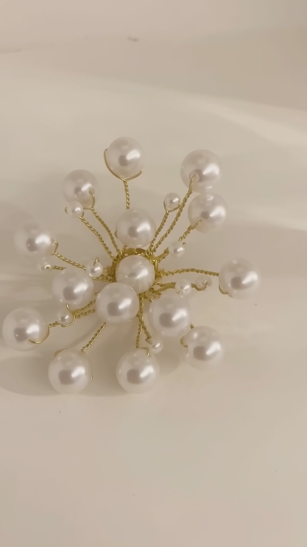 Video of the handmade Astra Pearl Burst Brooch by LUMI showing its white pearl beads and sculptural gold-tone branches from multiple angles.