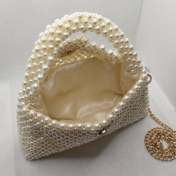Open view of The Nacre Bag showing its soft satin interior lining and pearl-covered structure.