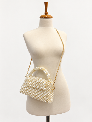 The Nacre pearl handbag displayed with its gold-tone shoulder chain on an ivory mannequin.